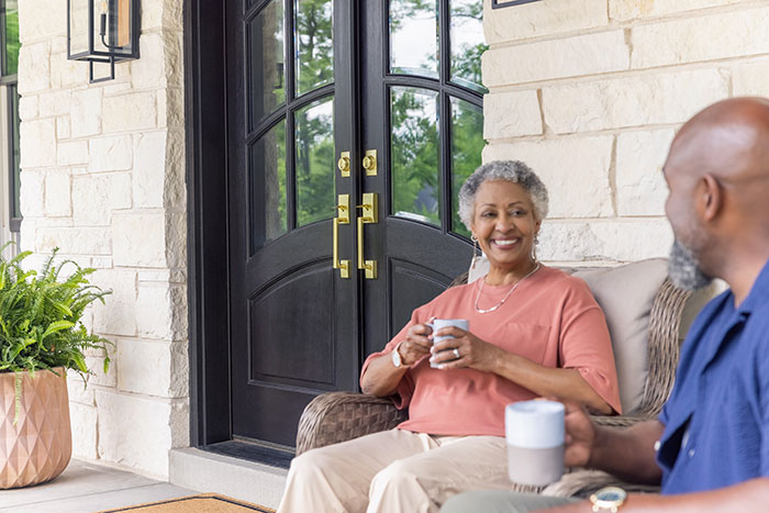 Senior couple sitting on their front porch with coffee.