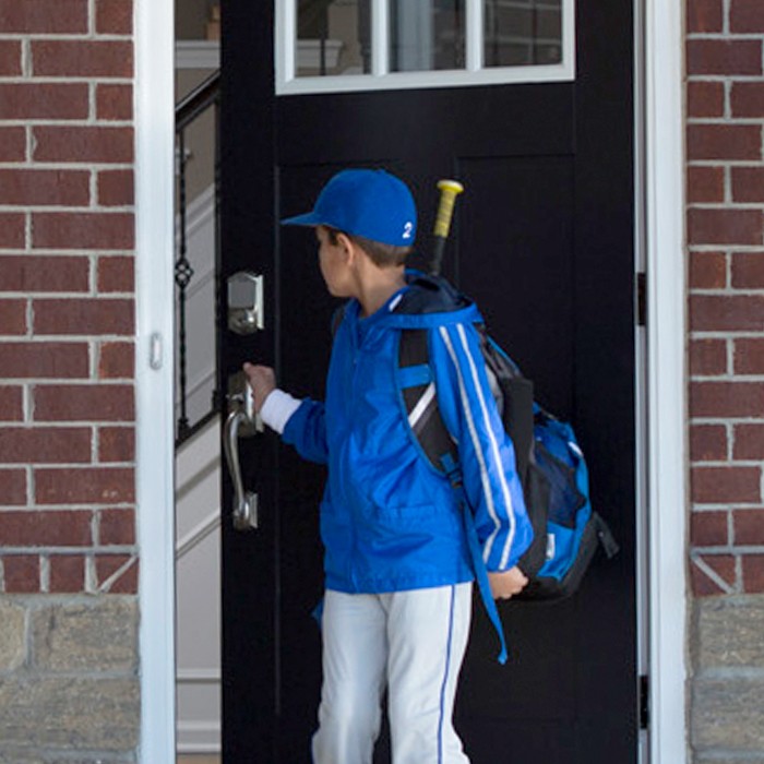 Pre-teen boy leaving his home dressed in a baseball uniform.