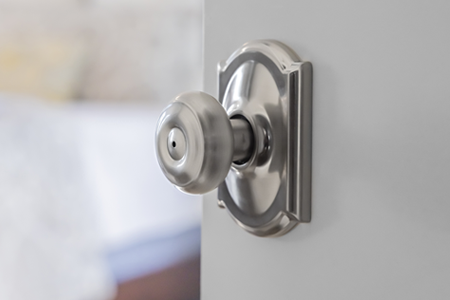 Close up of bedroom door featuring a traditional style door knob. 